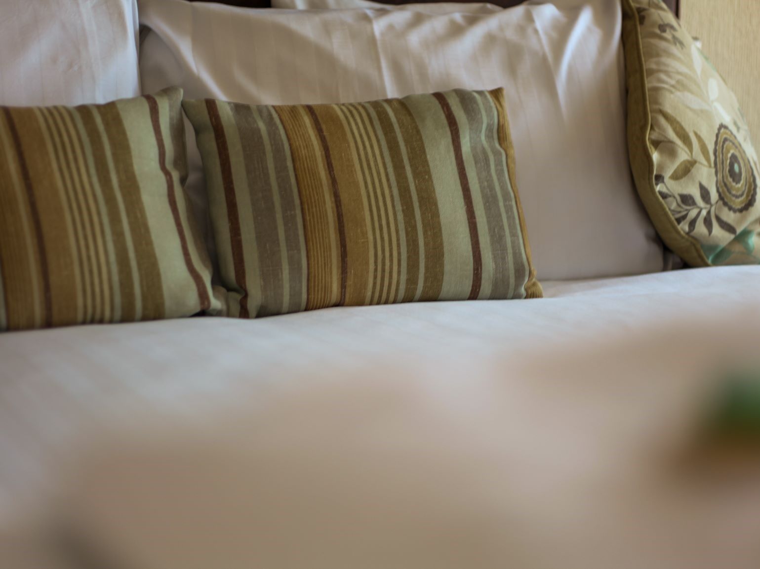 A bed with striped pillows and a decorative pillow with a floral pattern.