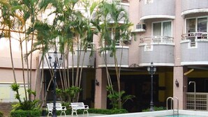 A swimming pool with a tiled deck, surrounded by palm trees and benches. - Summer Kenting B&B (Hengchun)