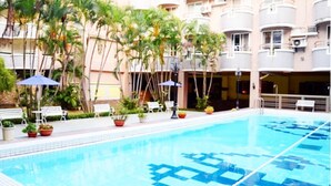 A swimming pool with a geometric pattern on the floor, surrounded by palm trees and benches. - Summer Kenting B&B (Hengchun)
