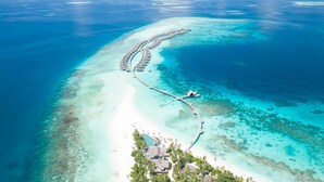 An aerial view of a resort with overwater bungalows connected by a walkway, surrounded by clear turquoise waters and white sand beaches. - JOALI Maldives (Muravandhoo)