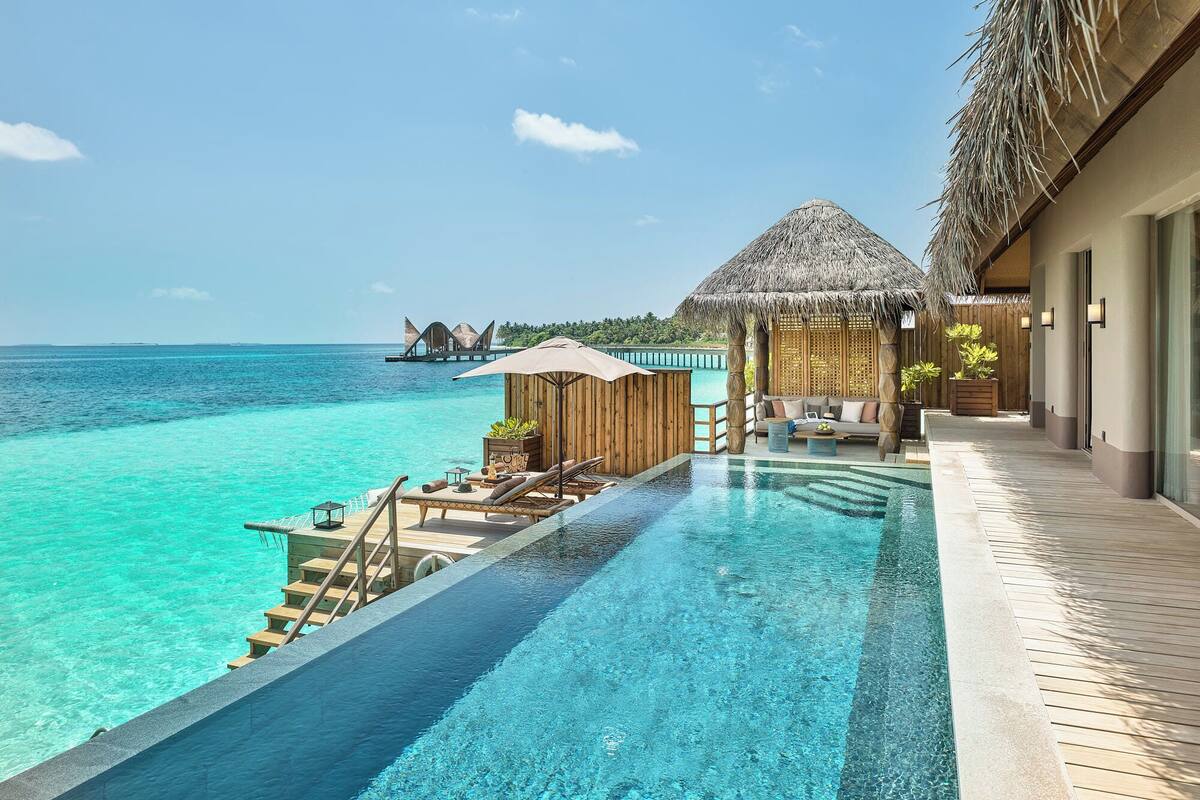 An infinity pool with a view of the ocean and overwater bungalows.