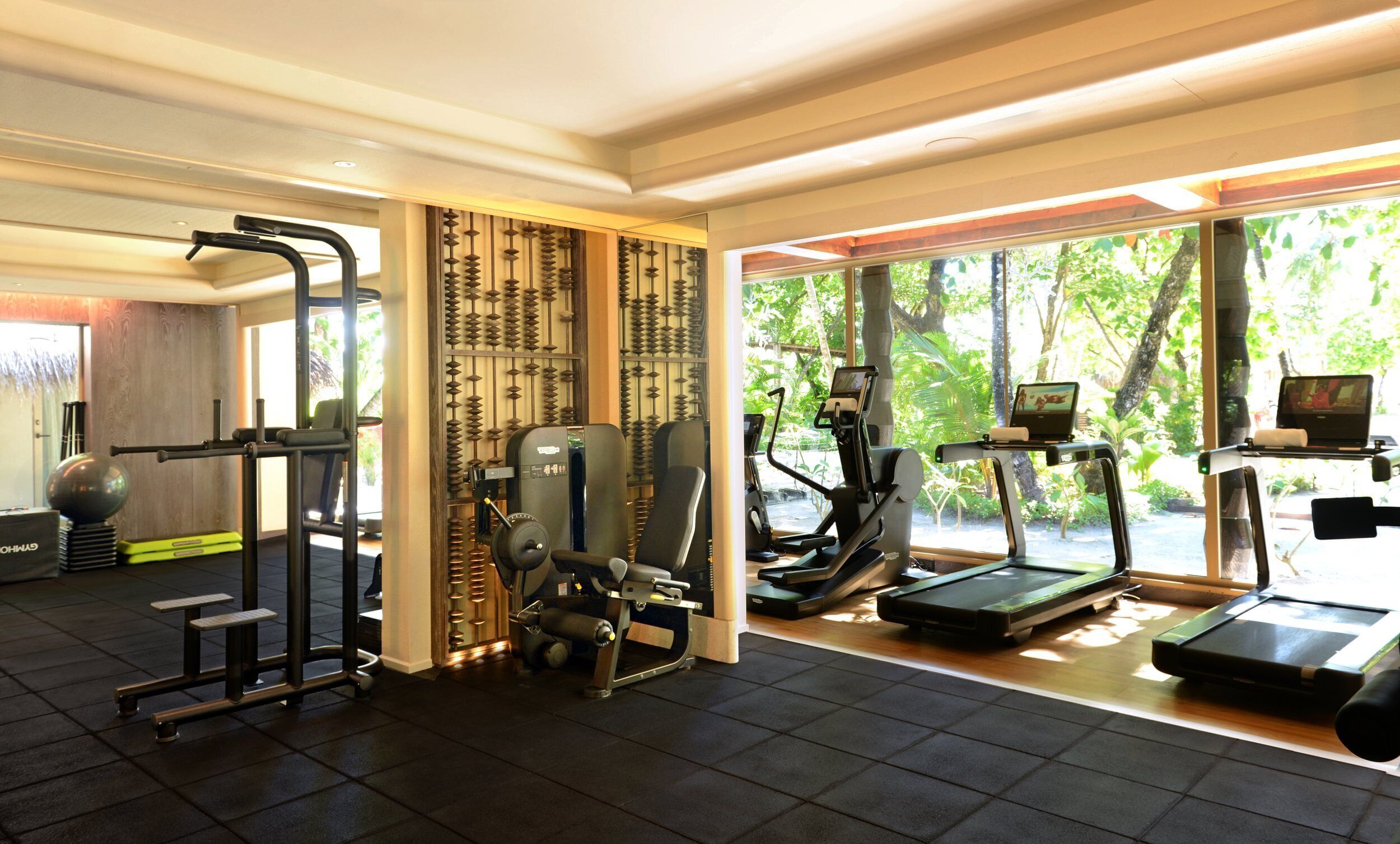 Uma academia com diversos equipamentos de exercício, incluindo esteira, elíptico e máquinas de peso.