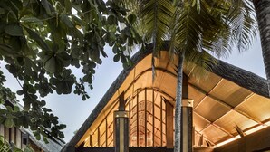 A large, open building with a high ceiling and a thatched roof, surrounded by tropical plants. - JOALI Maldives (Muravandhoo)