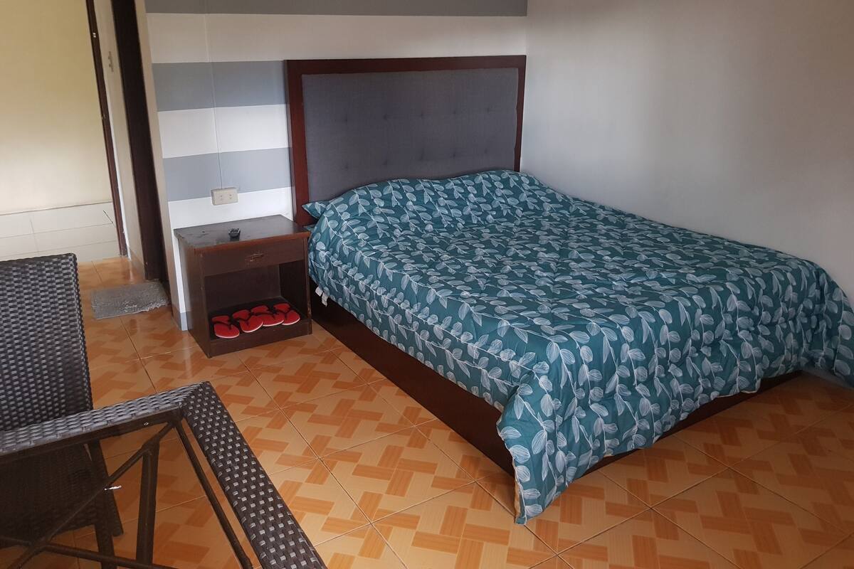 A bedroom with a bed, nightstand, and a small table with chairs.