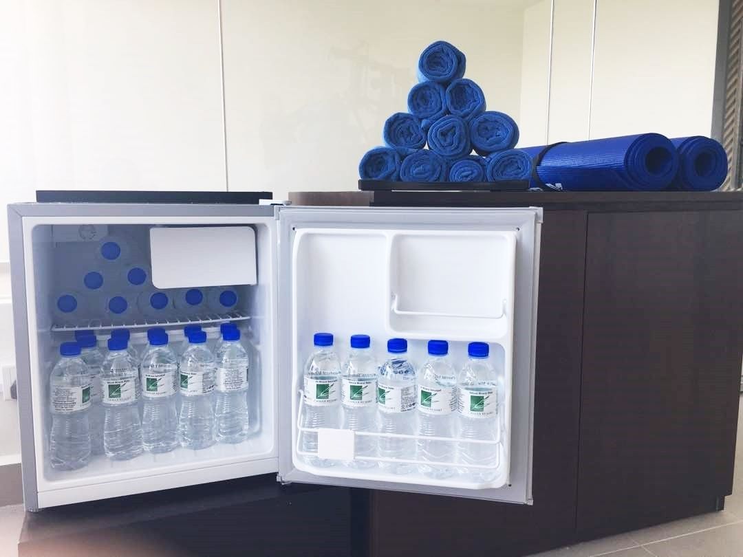 Ein Minikühlschrank mit Wasserflaschen und aufgerollten Yogamatten.