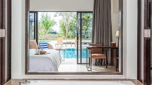 Un baño moderno con una bañera grande, un ventilador de techo y vistas a un área de piscina exterior con sofá y sillones.