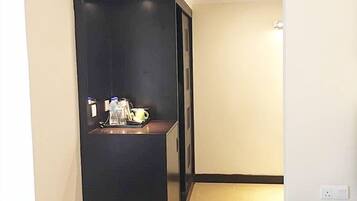 A compact hotel room with a kitchenette, a small table, and an air conditioning unit.