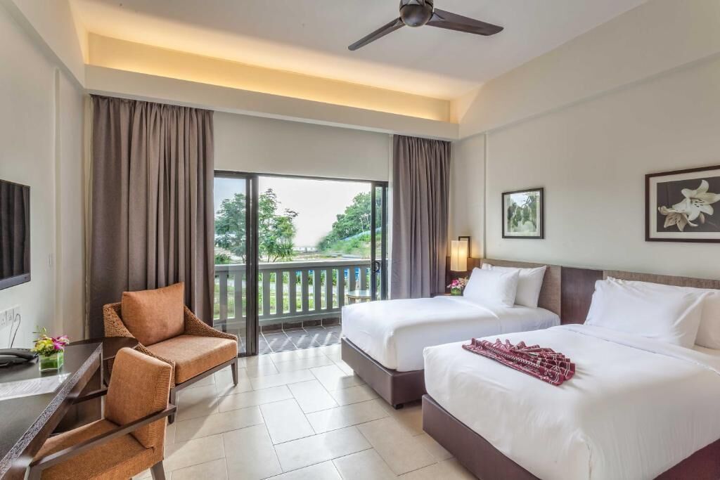 A hotel room with two beds, a sofa, a TV, and a balcony with curtains.