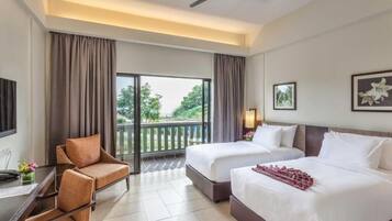 A hotel room with two beds, a sofa, a TV, and a balcony with curtains.
