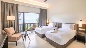 Una habitación de hotel con dos camas, un balcón, una silla, una mesa y un ventilador de techo.