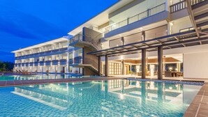 Un hotel con piscina, varios balcones y un diseño arquitectónico moderno.