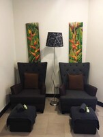 Una habitación con dos sillones oscuros, una lámpara de pie y dos otomanas.