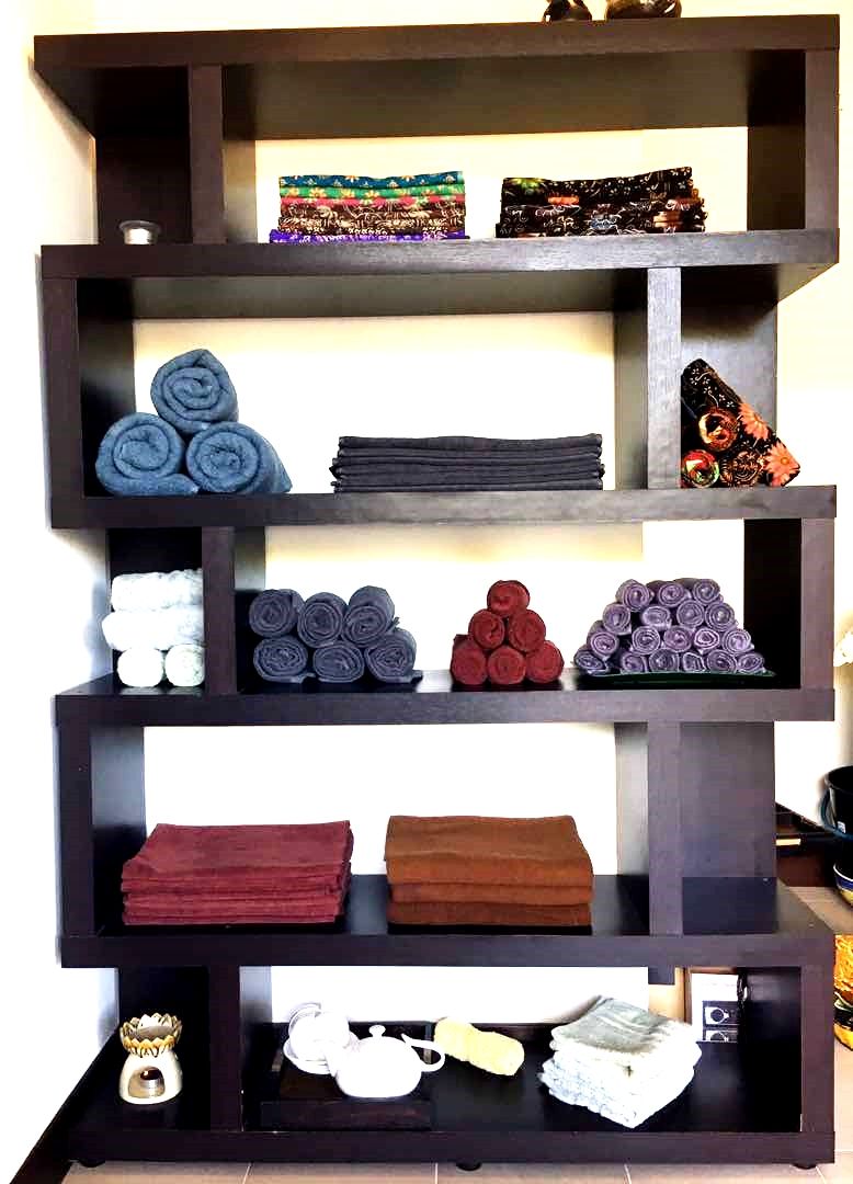 A multi-tiered wooden shelf unit with various textiles and decorative items.
