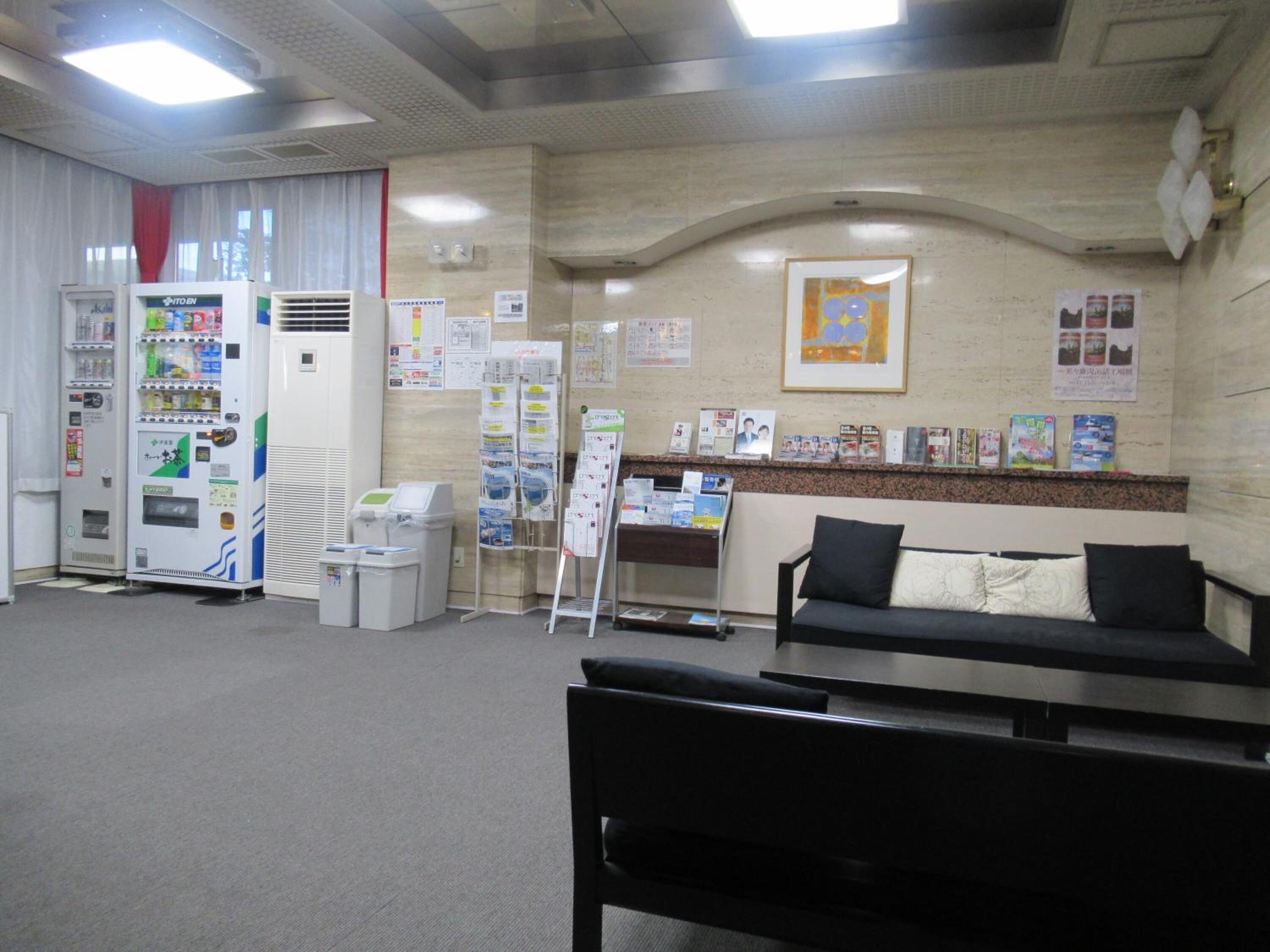 A reception area with a couch, a desk, a bulletin board, vending machines, and a trash bin.