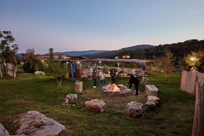 A rustic outdoor setting with a stone fire pit, seating areas, and a covered structure with string lights. - Yenice Vadi Dogal Yasam Koyu (Mugla)