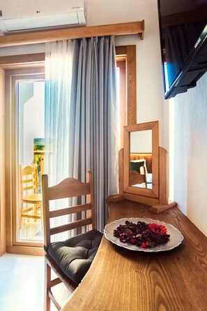 A corner room with a wooden chair, a small table with a plate of flowers, a mirror, and a window with curtains. - Yenice Vadi Dogal Yasam Koyu (Mugla)