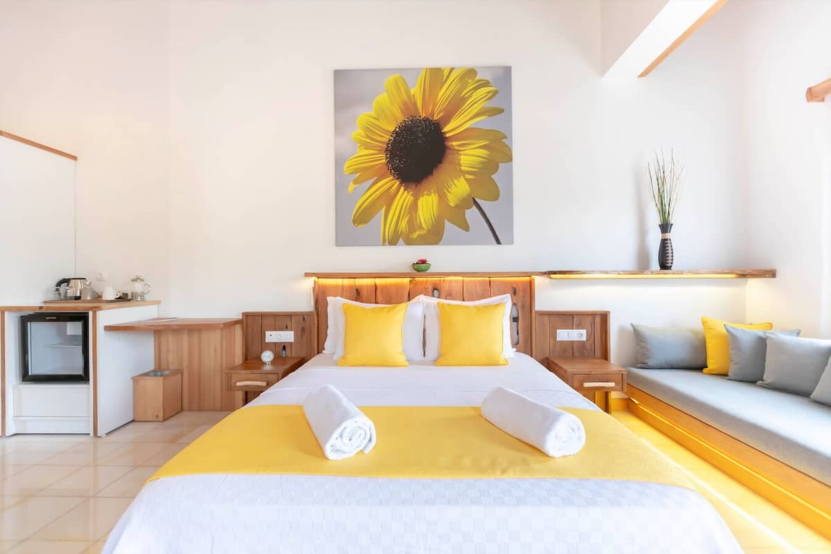 Ein modernes Hotelzimmer mit einem großen Bett, einer kleinen Küchenzeile, einem Sofa und einem wandmontierten Regal.