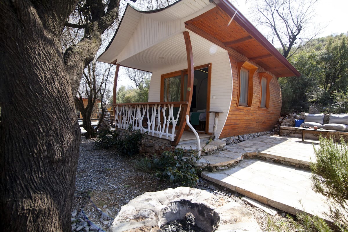 Eine Holzhütte mit Veranda, Steinstufen und einer Feuerstelle.