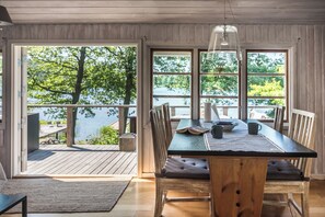 Una mesa de comedor de madera con vistas a un lago a través de grandes ventanales.
