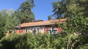 Un bâtiment rouge avec un toit en tuiles, entouré de verdure et d’arbres.