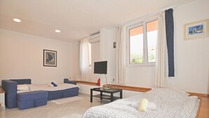 A modern bedroom with a bed, a sofa, a TV, and a window with curtains.
