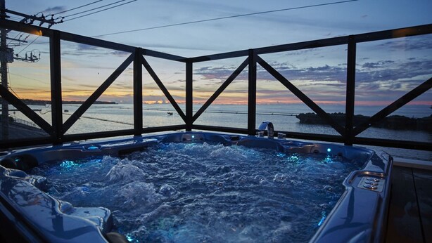 A hot tub with a sunset view through a metal framework. - T&T Vacation Rentals (Onna)