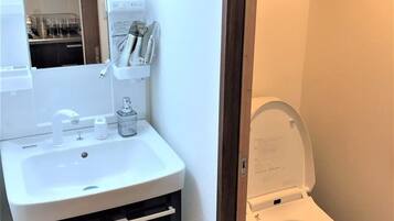 A bathroom with a white sink, dark cabinet, and a white toilet.