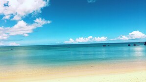 A beach with clear turquoise water, a sandy shore, and scattered rocks. - T&T Vacation Rentals (Onna)