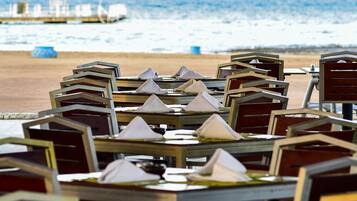 Un restaurante frente al mar con mesas y sombrillas, con vista al océano.