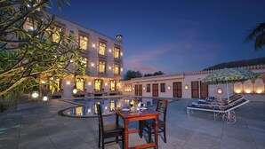 A courtyard with a pool, a dining table with chairs, and a lounge area with a parasol. - Ranthambhore National Resort (Sawai Madhopur)