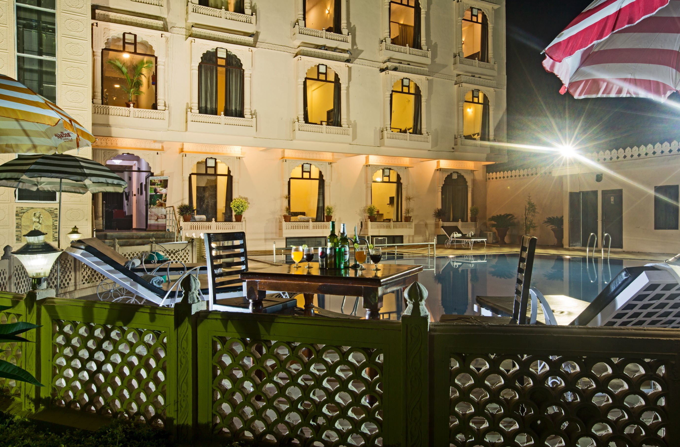 Un hotel con piscina, mobiliario exterior y fachada bien iluminada.