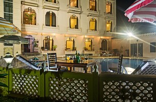 Un hotel con piscina, mobiliario exterior y fachada bien iluminada.