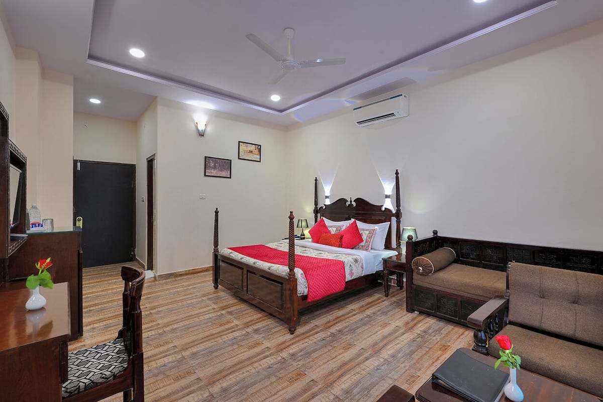 Une chambre d’hôtel avec un lit à baldaquin, un canapé, un bureau avec une chaise et une table à manger.