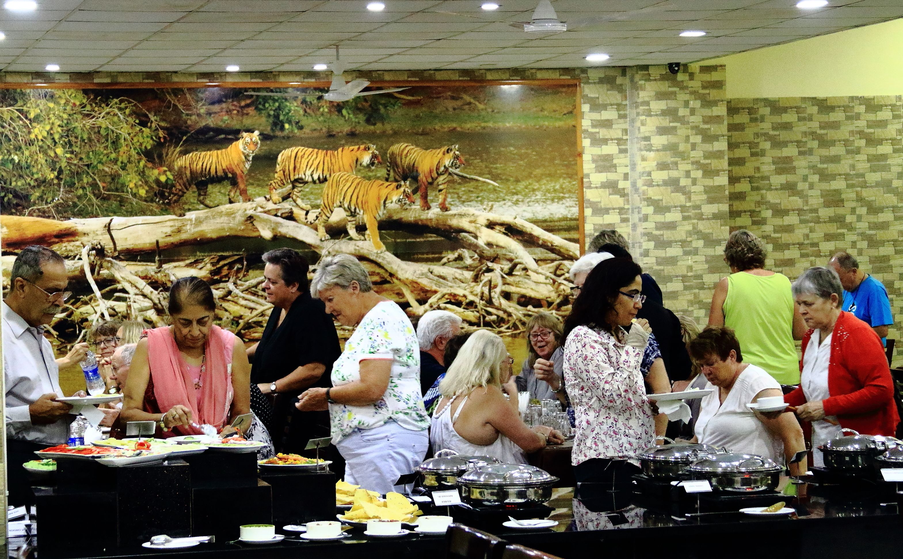 Een buffet met diverse gerechten en een tijgerschildering op de achtergrond.