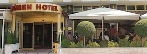 Guests can dine or relax in the outdoor seating areas beneath the hotel's curved sign.