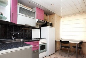 Compact kitchen with sink, gas stove, oven, and microwave, adjacent to a dining area with a table and chairs.