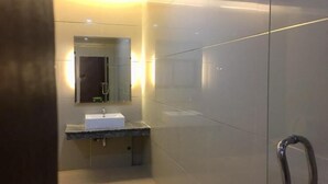A modern bathroom with a marble countertop, a white sink, and a glass shower enclosure. - Visa Hotel (Bangkok)