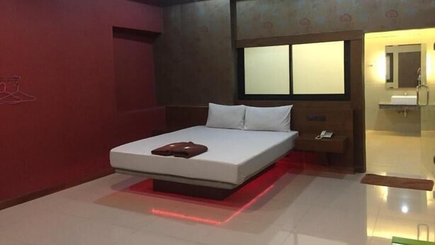 A modern hotel room with a large bed, a bedside table, and a mirror. - Visa Hotel (Bangkok)