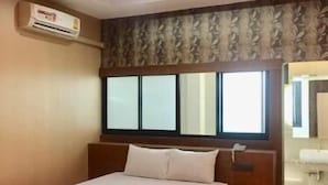 A hotel room with a bed, a window, an air conditioning unit, and a bathroom visible through the door. - Visa Hotel (Bangkok)