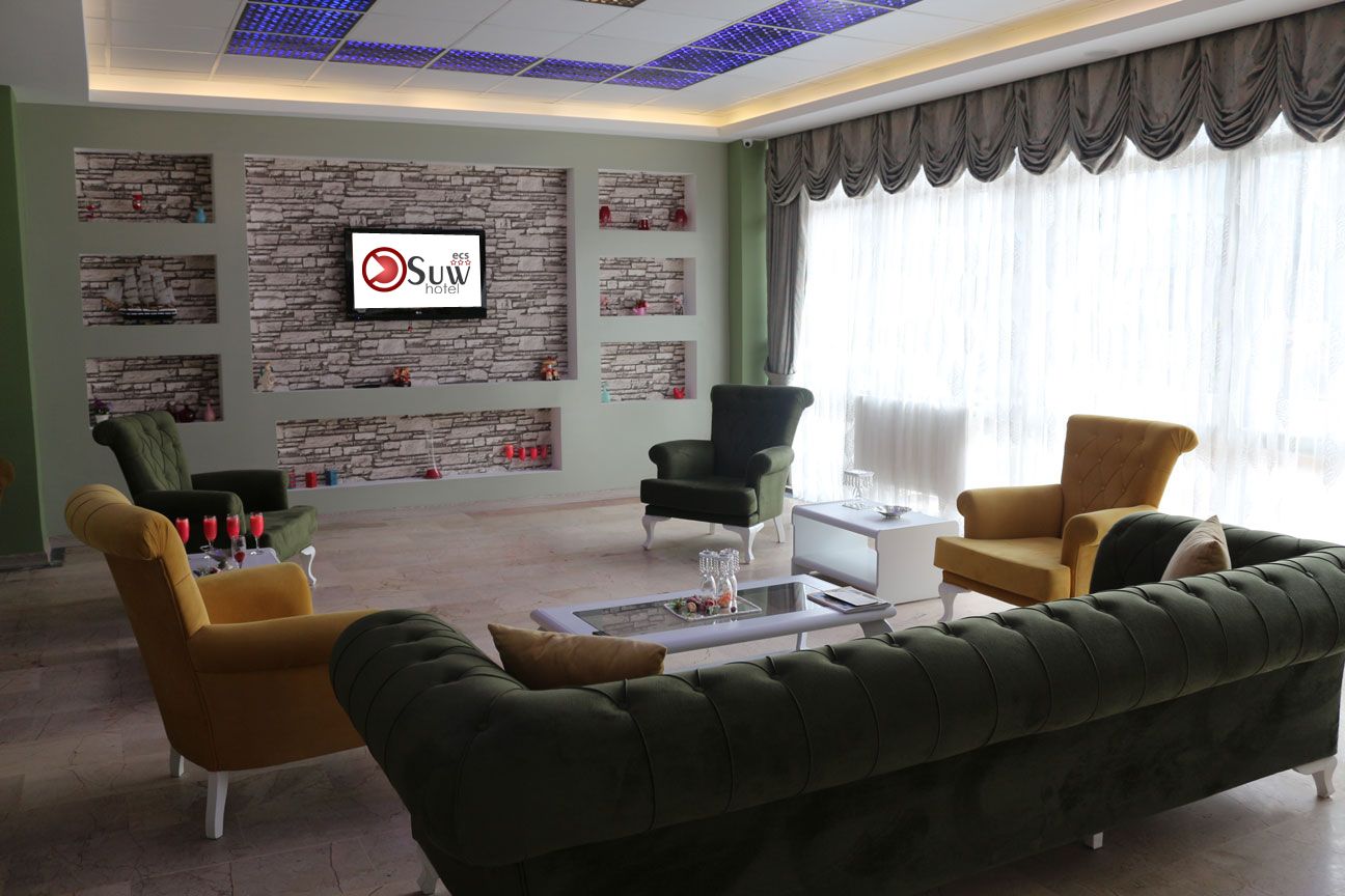 Una sala de estar moderna con sofá, sillones y una mesita de centro. Un televisor de pantalla plana está montado en la pared.