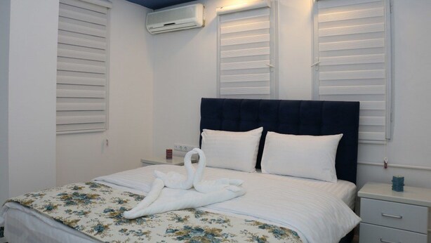 A hotel room with a bed, a nightstand, and a wall-mounted air conditioner. - Suw Hotel (Atakum)