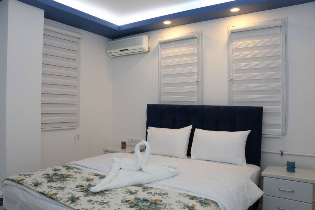 Ein Hotelzimmer mit Bett, Nachttisch und Wand-Klimaanlage.