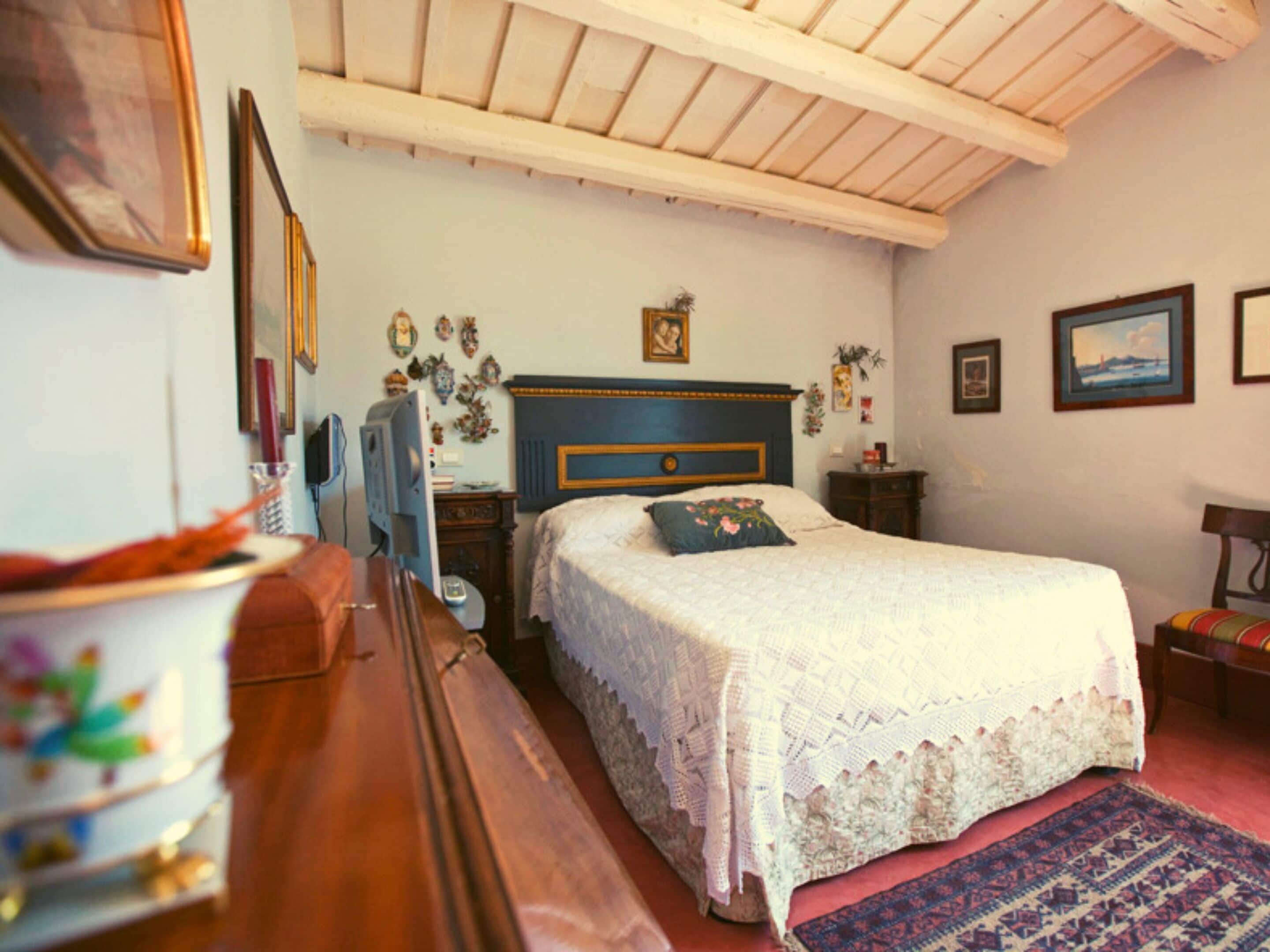 A bedroom with a wooden bed, a desk, a chair, and a television.