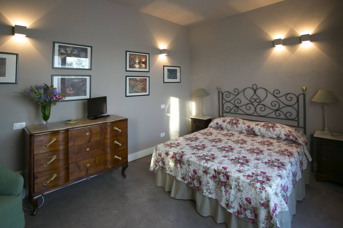 A bedroom with a bed, dresser, and wall-mounted artwork.