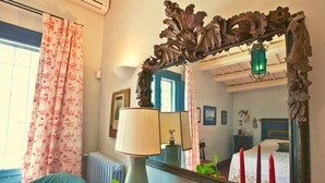 Una habitación con cama, espejo, radiador, lámpara y una mesa con fruta.