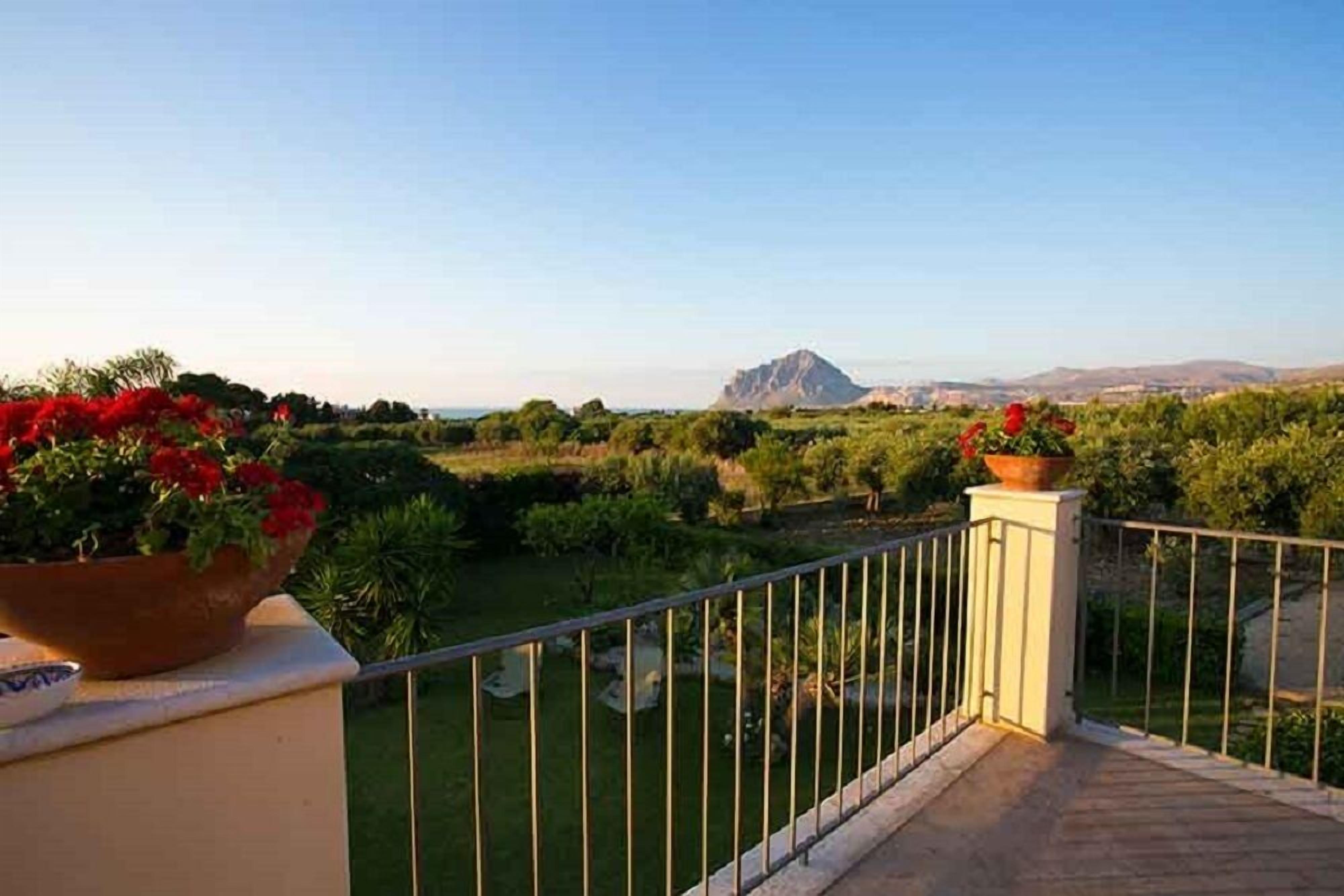 A balcony with a view of a landscaped garden and distant mountains.
