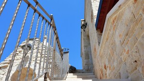 A staircase with a metal railing leading up to a stone building.