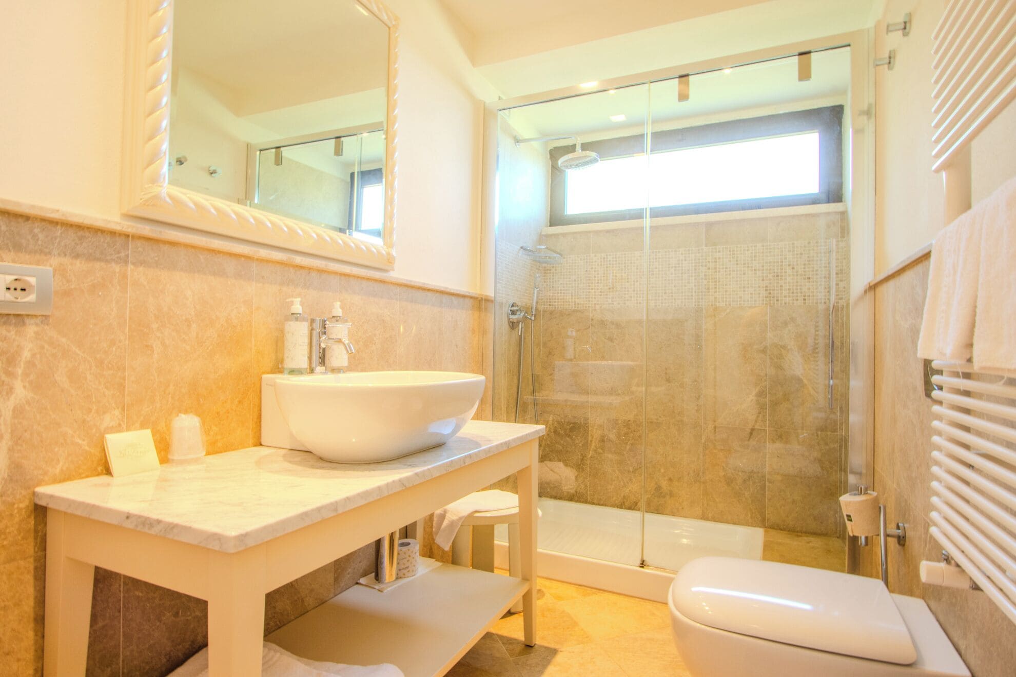 Un baño con lavamanos grande, espejo, ducha e inodoro.