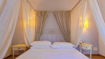 Un letto a baldacchino, due comodini, una lampada a parete e un telefono sul comodino.