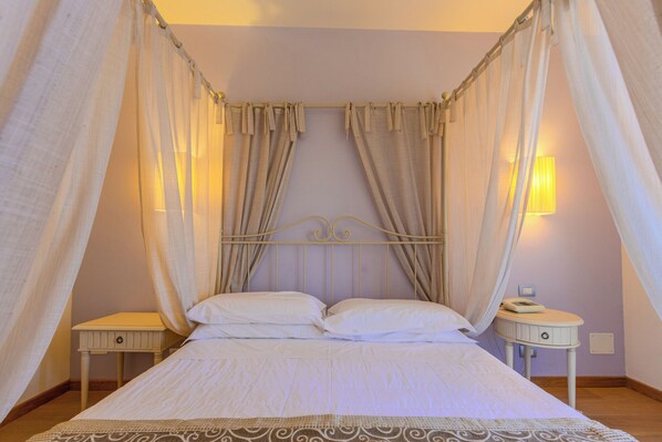 A bed with a canopy, two bedside tables, a wall-mounted lamp, and a bedside telephone. - Hotel Girifalco - Nature & Relax (Massa Marittima)